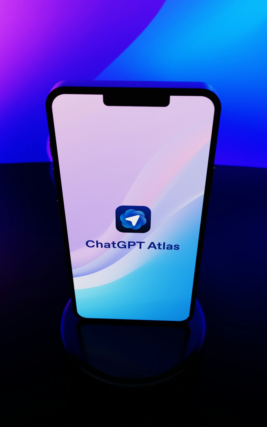 ChatGPT Atlas app displayed on a modern smartphone with sleek gradient background blending vibrant purple, blue, and cyan colors. The minimalist interface showcases the distinctive blue messenger-style icon and app branding on a device with dynamic island design. Perfect representation of cutting-edge AI technology, mobile applications, and contemporary digital innovation in artificial intelligence communication tools.